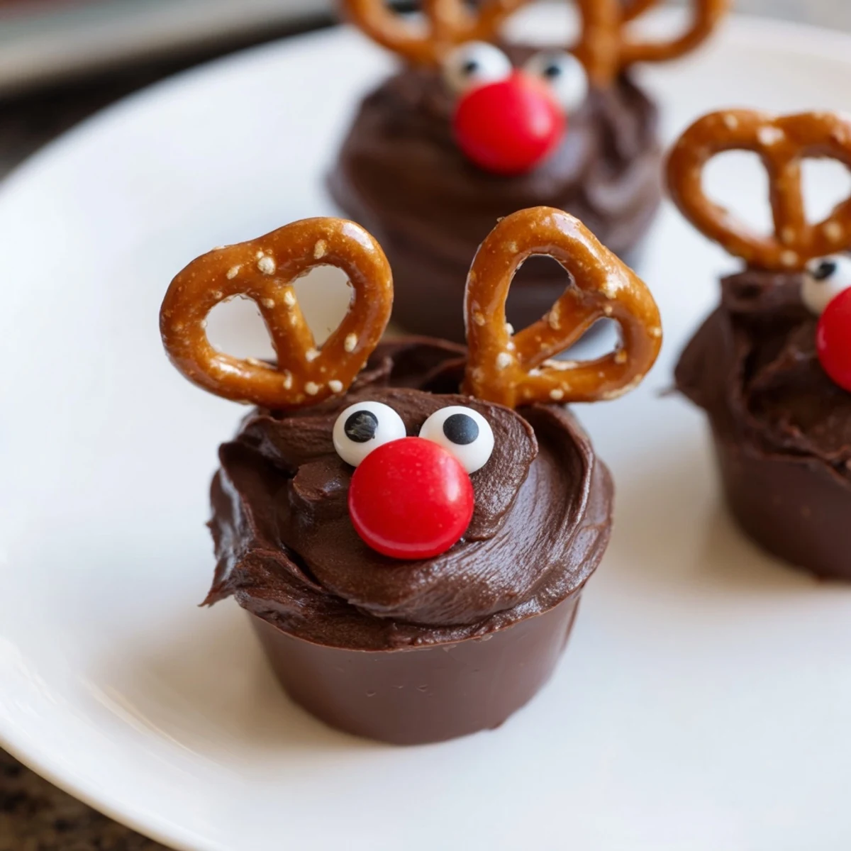 Homemade chocolate pudding cups creatively decorated as reindeer with pretzels and candy features.