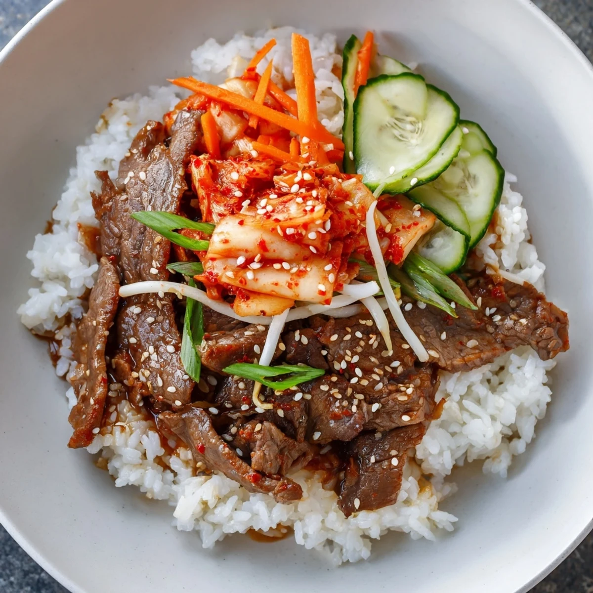 Tender, savory bulgogi beef bowl with glistening marinated meat alongside fresh vegetables and rice.