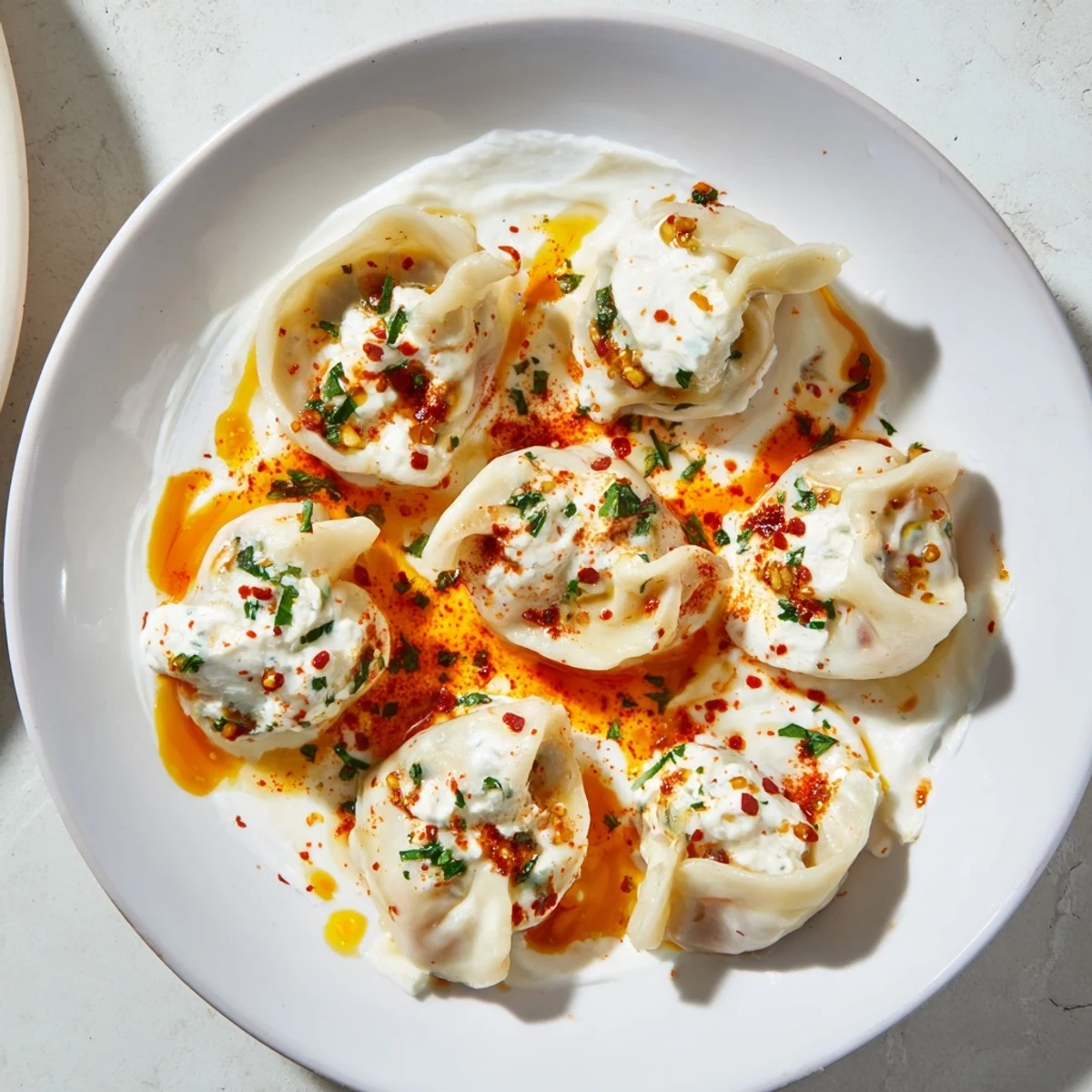 Steaming Turkish cheesy manti dumplings topped with tangy yogurt sauce and spicy butter drizzle.