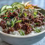 This quick 25-minute Korean beef bowl features tender ground beef in a glossy red sauce, topped with crunchy sesame seeds and vibrant green onions.