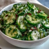 Fresh cucumber radish salad with dill vinaigrette, crisp and colorful, served in a white bowl with dill garnish.  