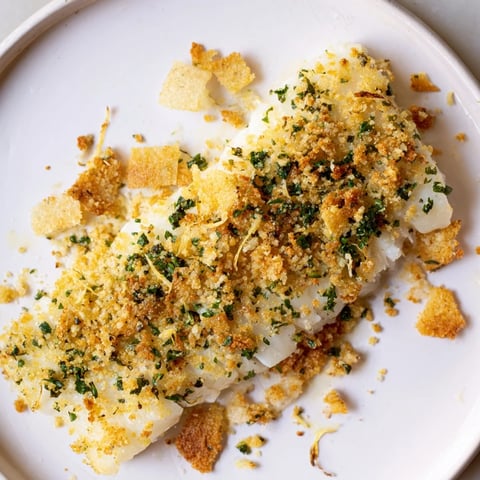 Golden-brown Baked Cod with Crispy Ritz Cracker Topping, ready to serve with lemon wedges.