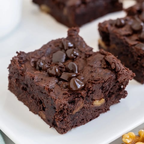Warm, fudgy Greek yogurt brownies topped with melted chocolate chips, a delicious dessert treat.