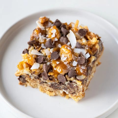 A rich image of 7-Layer Magic Bars, showing a drizzle of salted caramel on delicious layers.