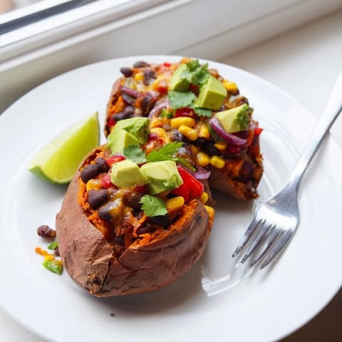 Steaming baked sweet potatoes loaded with black beans, avocado, and fresh lime, a hearty vegetarian meal.