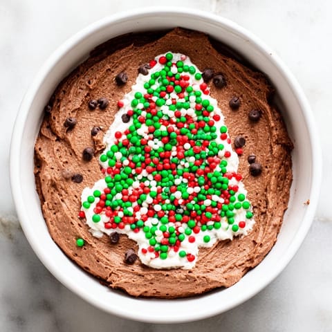 Festive Tree Brownie Dip, swirled with sprinkles, served with pretzel sticks and fresh strawberries.