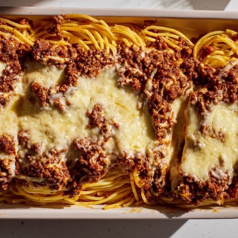 A close-up of Tinis Baked Spaghetti, showing the layers of cheese, meat, and perfectly cooked noodles.
