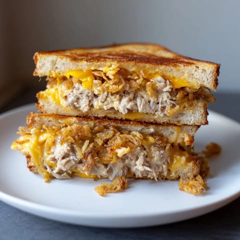 Warm, crispy-edged Crispy Shallot Chicken Grilled Cheese ready to be sliced, perfect for lunch.
