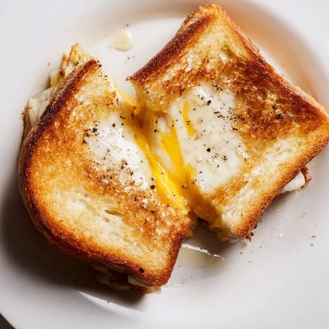 A close-up of a perfectly toasted Truffle Oil Grilled Cheese, oozing melted cheddar, served on a plate.