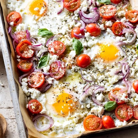 Easy sheet pan Tomato Feta Baked Eggs: Imagine sun-ripened tomatoes and runny egg yolks with crumbled feta.