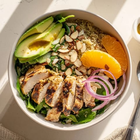 Grilled herb chicken rests atop fluffy quinoa and fresh greens in this colorful Citrus Herb Chicken Salad Bowl.
