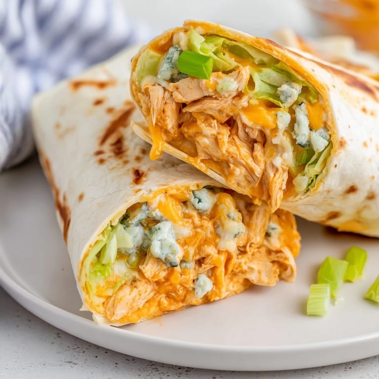 A close-up of a perfectly grilled and sliced buffalo chicken dip wrap offering a delicious first bite.