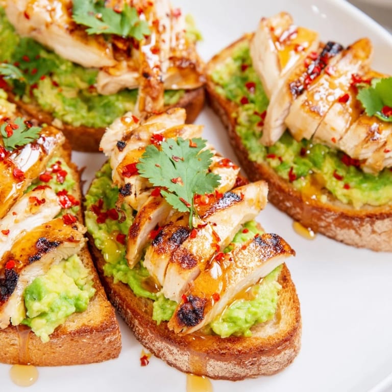 Smashed Avocado Chicken Toast features crusty bread, tender sliced chicken, vibrant avocado mash, and a honey-chili finish for an easy brunch dish.