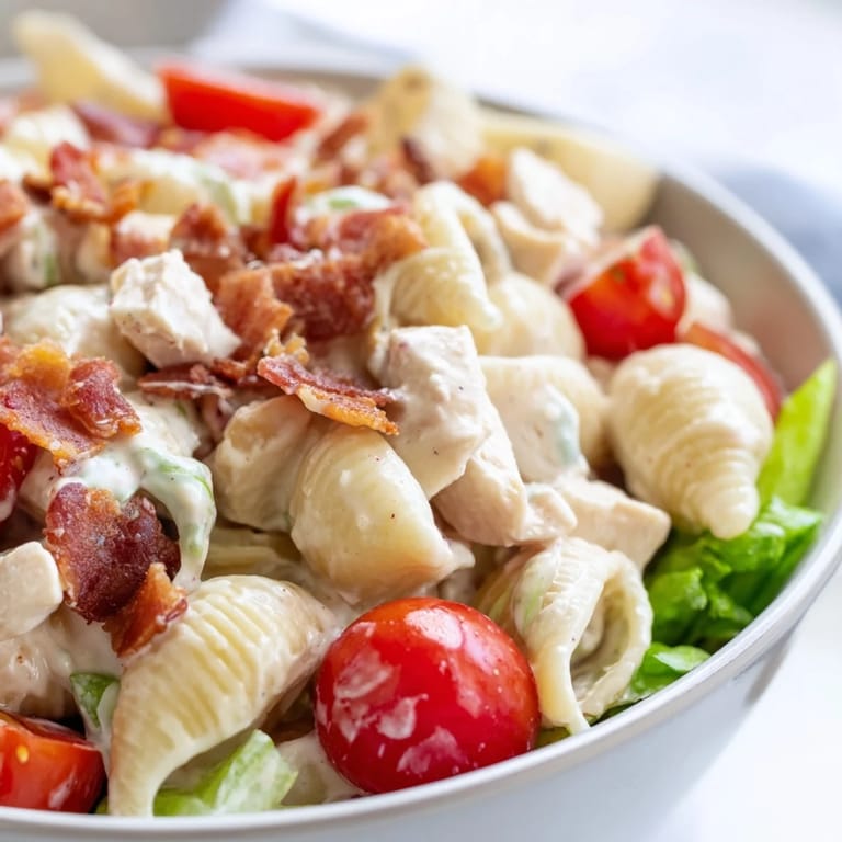 Serving suggestion for BLT Chicken Pasta Salad, presented on a picnic blanket with a fork, showcasing the colorful mix of smoky bacon, grilled chicken, crunchy lettuce, and tomatoes for an easy summer lunch.