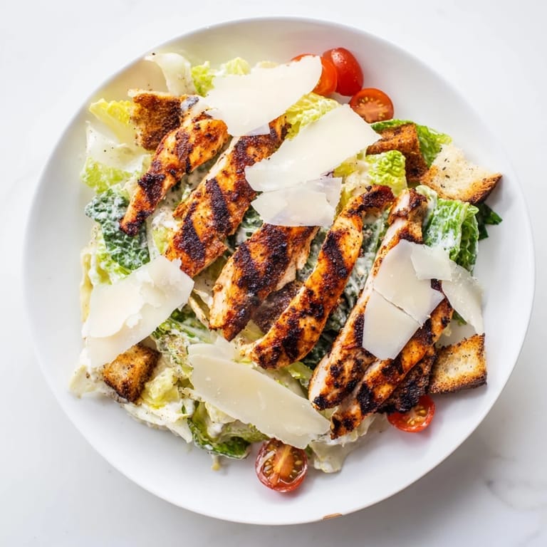 A vibrant serving of Yogurt Caesar Grilled Chicken Salad with golden chicken strips, creamy dressing, and crunchy romaine and croutons.