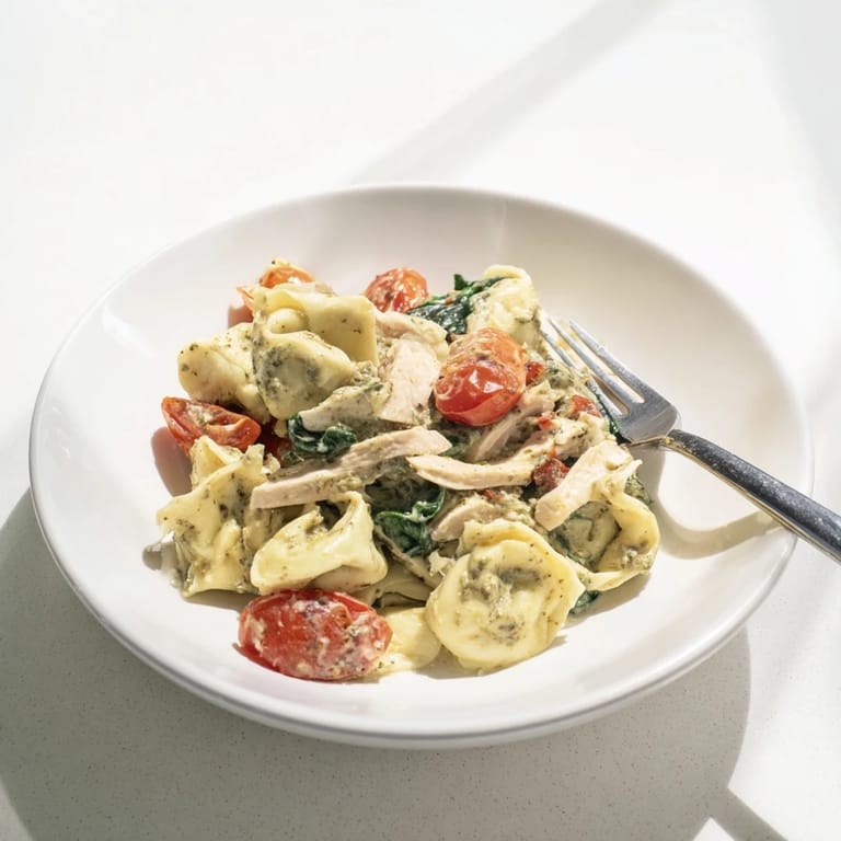 This comforting Italian-American main dish features tender cheese tortellini coated in a rich basil pesto cream sauce, served hot from the skillet.  